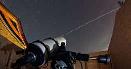La Station Spatiale Internationale et la Navette Spatiale Discovery traversant le ciel devant le télescope d'un observatoire.